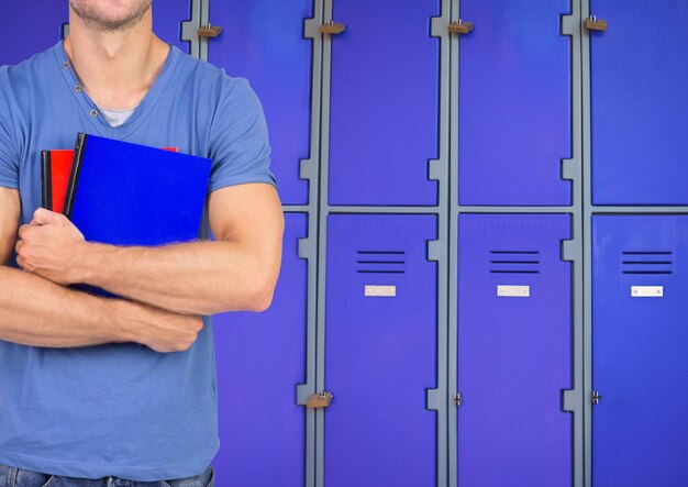 male student holding books in front of lockers