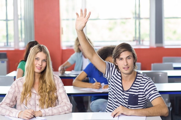 Foto studente maschio che solleva mano in aula