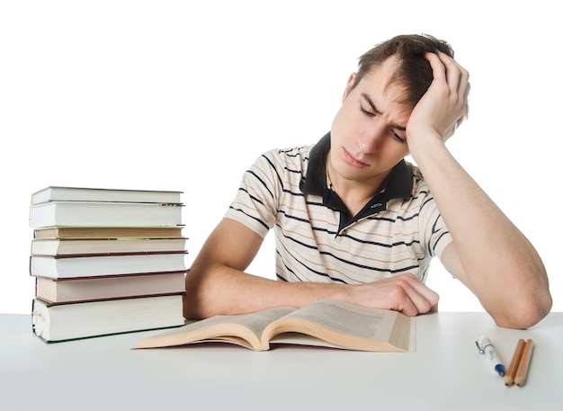 Male student at the table with a pile of books over white