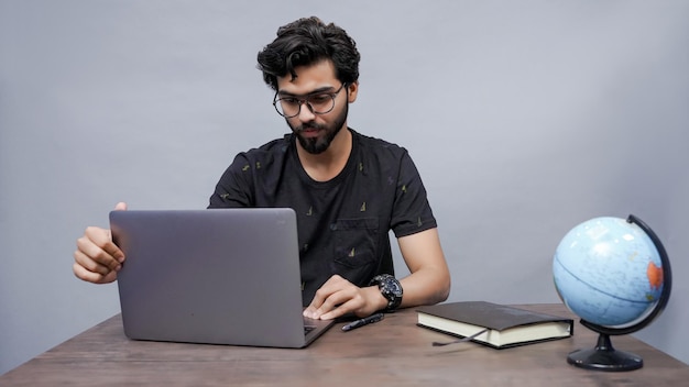 male student using laptop for study wearing black watch sitting on the table indian pakistani model