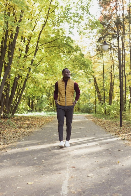 Photo male student walking in the park in autumn season