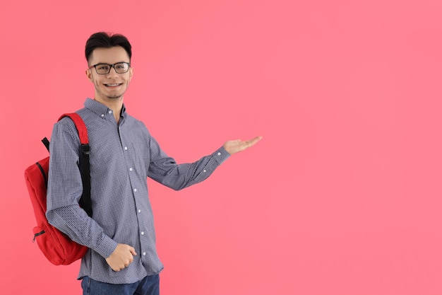 Male student with backpack on pink background