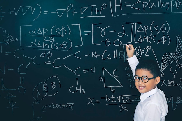 Male student writing mathematical formula in class