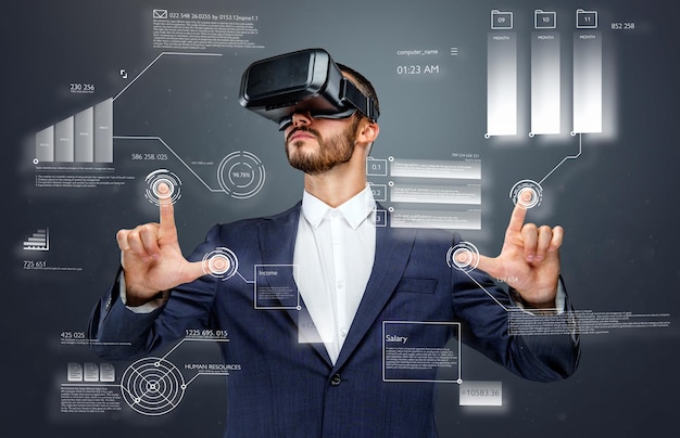 Male in a suit with virtual reality glasses on his head working in virtual financial world.