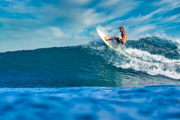 Male surfer on a blue wave at sunny day