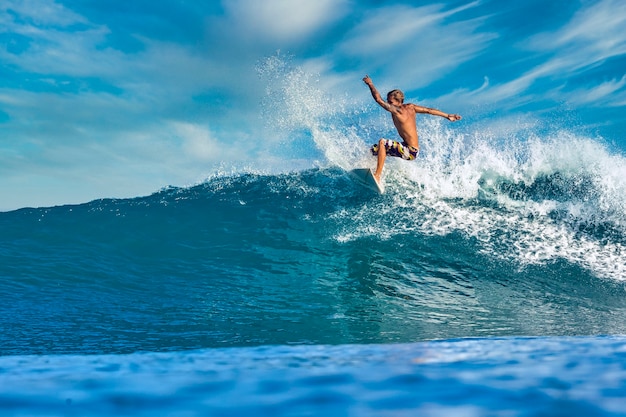 Male surfer on a blue wave at sunny day