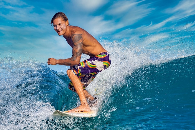 Male surfer on a blue wave at sunny day