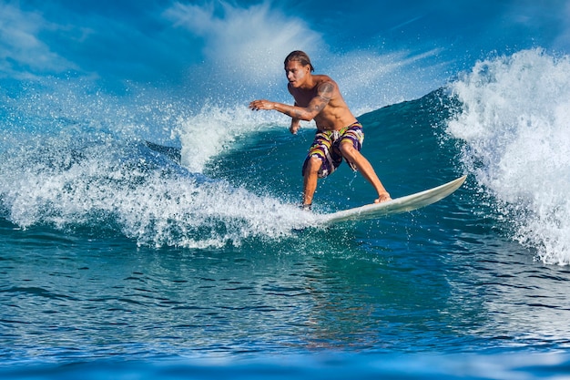 Male surfer on a blue wave at sunny day