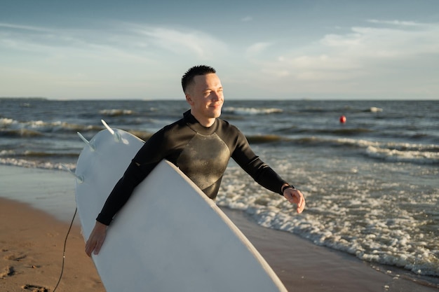 A male surfer goes in for sports at sea uses a surfboard in a
wetsuit