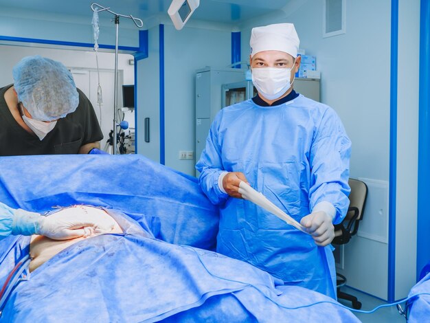 A male surgeon near the operating table removes the glove