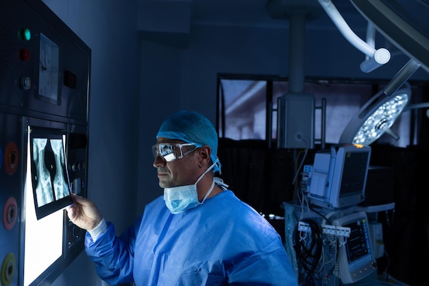 Photo male surgeon reading x ray in operating room at hospital