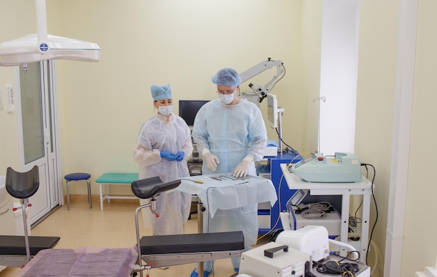 A male surgeon together with an assistant lays out sterile instruments to prepare for surgery