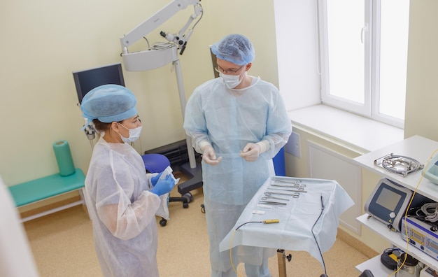 A male surgeon together with an assistant lays out sterile instruments to prepare for surgery