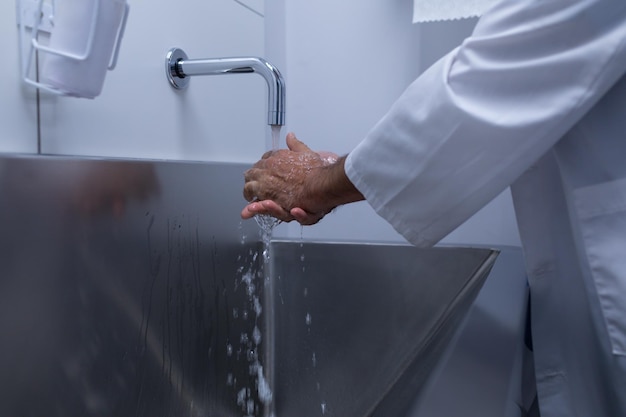 Male surgeon washing hands in sink at hospital