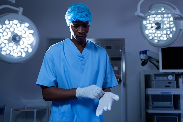 Male surgeon wearing surgical gloves in operating room at hospital