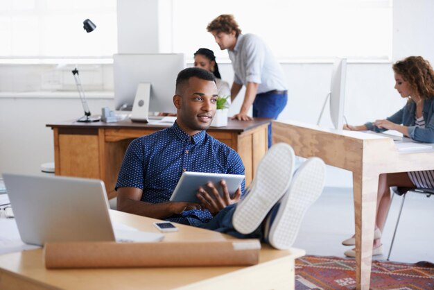 Male tablet and laptop in office with desk for thinking research or business African person and architect with technology internet or web online for design innovation and planning in Dublin