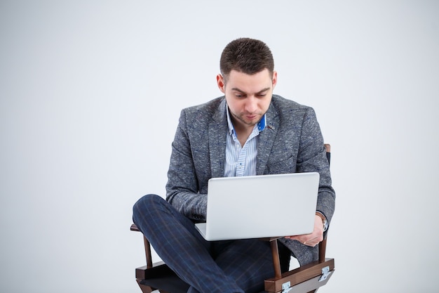 Бизнесмен директор-мужчина учитель, сидя на стуле, изучая документы. Он смотрит на экран ноутбука. Новый бизнес-проект.