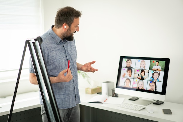 Foto insegnante maschio che ha una conferenza online con i bambini delle scuole che lavorano a casa