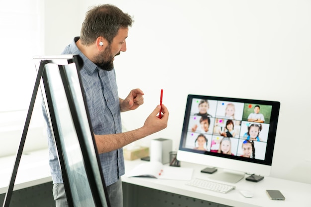 Insegnante maschio che ha una conferenza online con i bambini delle scuole che lavorano a casa