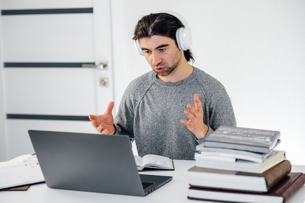 Male teacher wearing wireless headphones holding online lesson