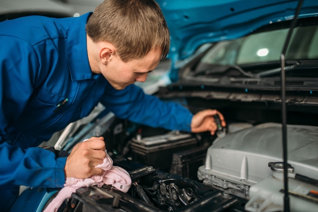 Male technician checks brake fluid level in car