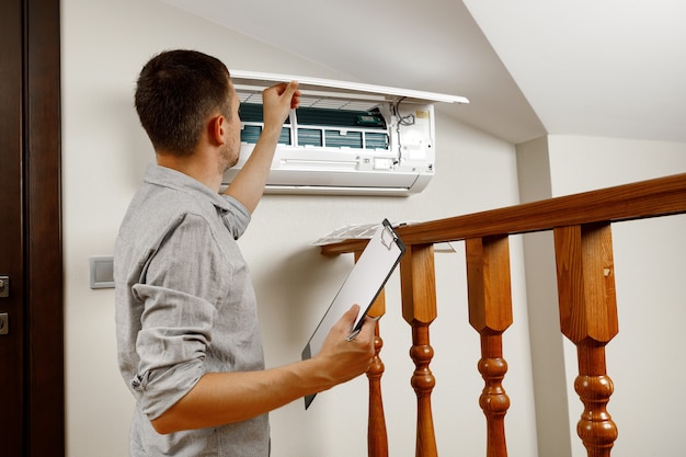 Male technician cleaning air conditioner indoors. a man with a tablet in his hands