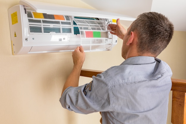 Male technician cleaning air conditioner indoors