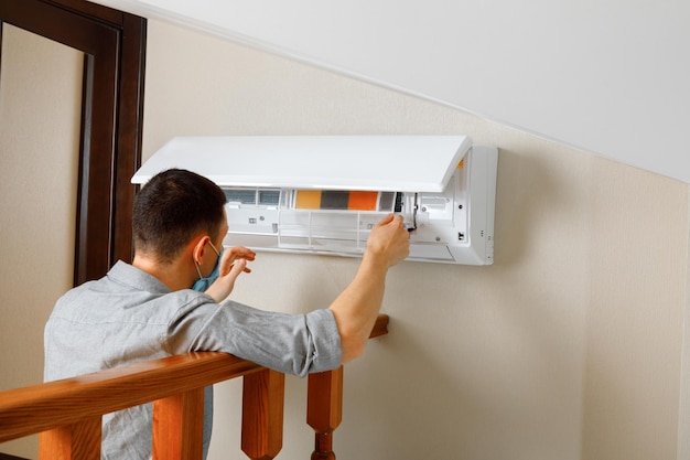 Male technician cleaning air conditioner indoors