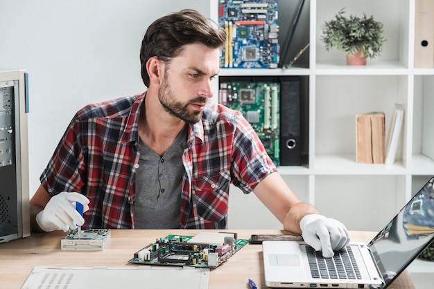 Male technician looking at laptop while repairing computer