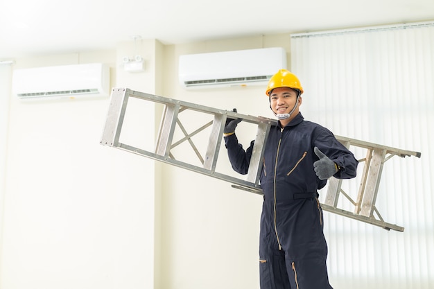 Male technician repairing air conditioner safety uniform indoors. 