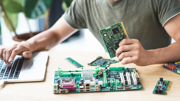 Male technician repairing motherboard using laptop