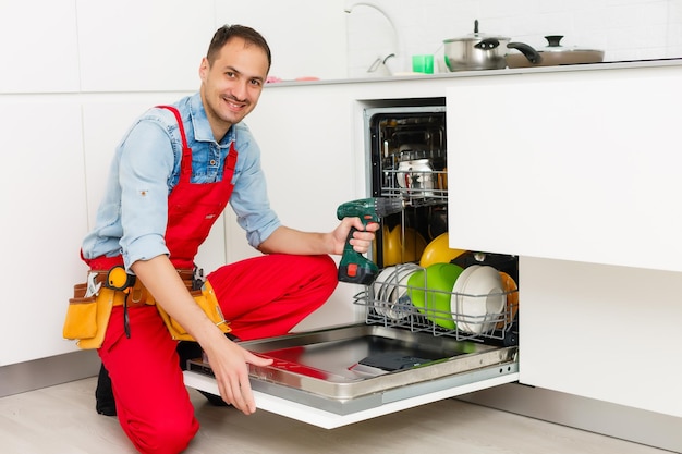 Male Technician Sitting Near Dishwasher In Kitchen