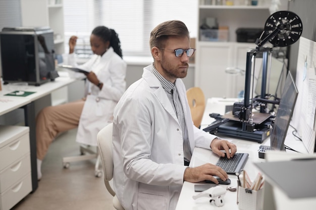 Male technician using computer in d printing lab