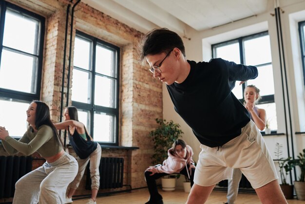 Male teenager in activewear bending forwards with his arms\
stretched behind back