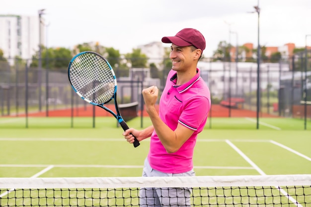 Male tennis player at the court looking happy