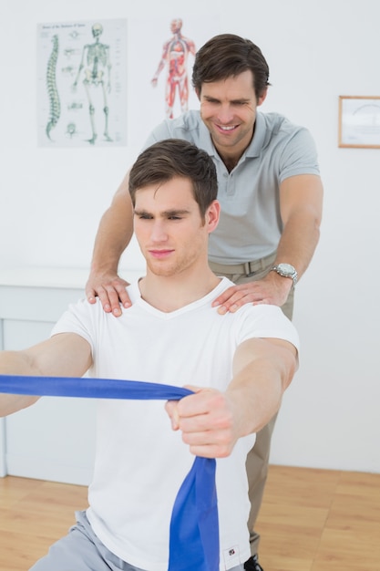 Male therapist assisting man with exercises in office