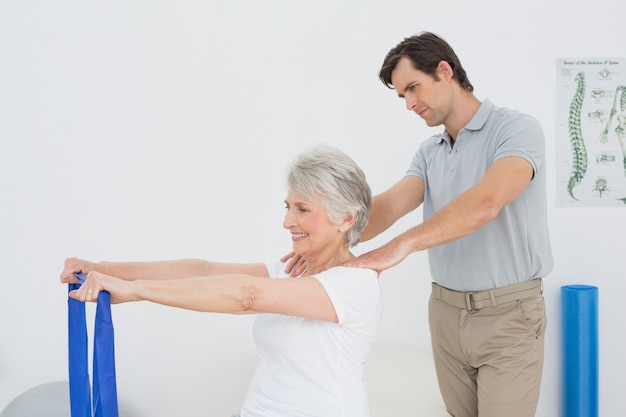 Male therapist assisting senior woman with exercises