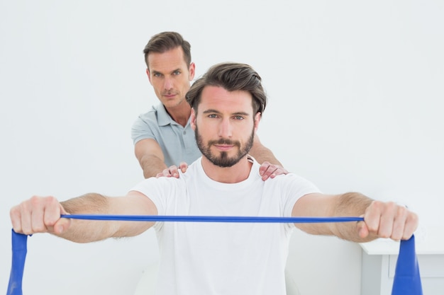 Male therapist assisting a young man with exercises