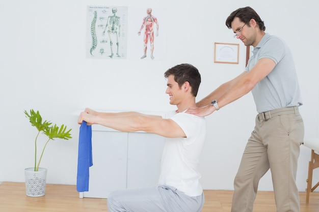 Male therapist assisting young man with exercises