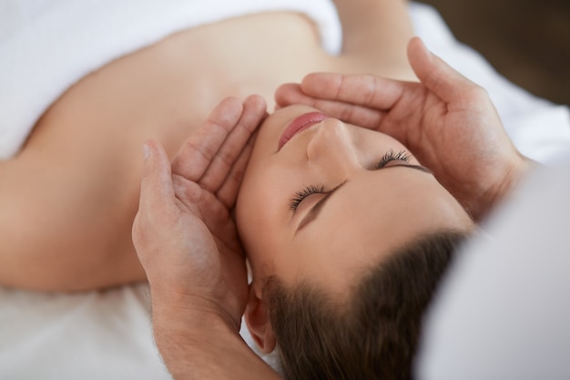 Male therapist making head massage to female client.