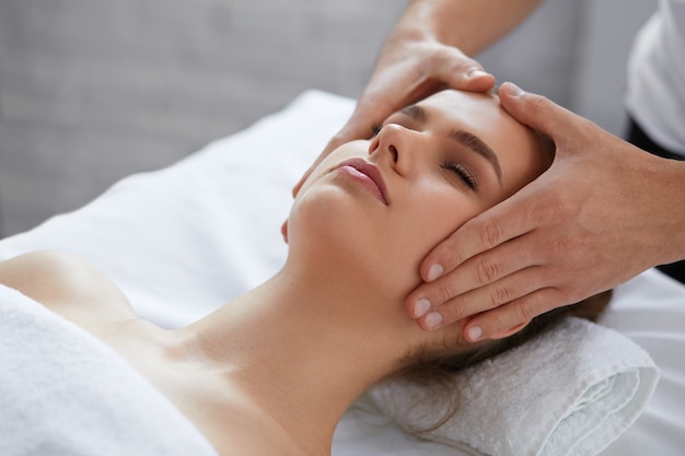 Male therapist making head massage to female client.