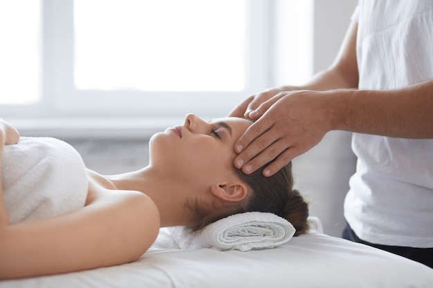 Male therapist making head massage to female client.