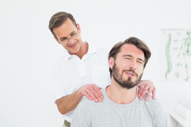 Male therapist massaging a content mans shoulders