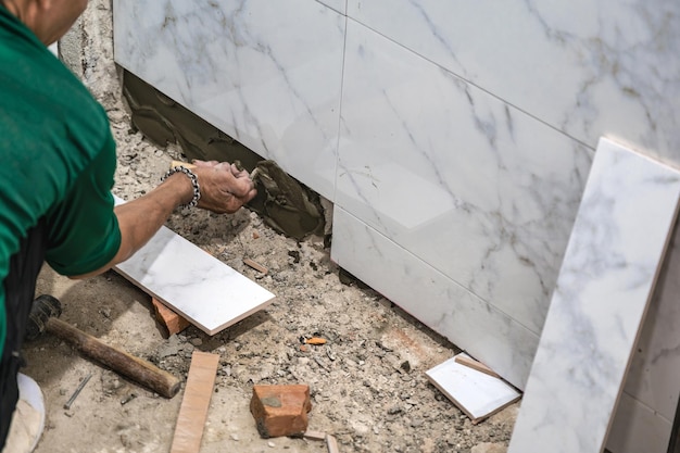 Photo male tiler using trowel laying marble tile with cement in bathroom housing development interior improvement renovation