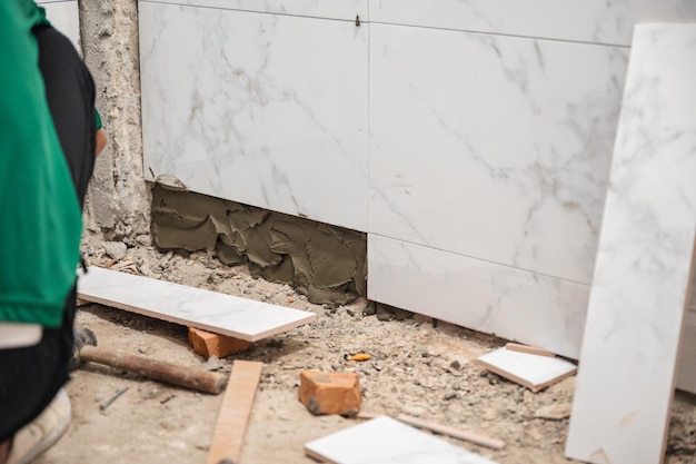 Male tiler using trowel laying marble tile with cement in bathroom Housing development Interior improvement renovation