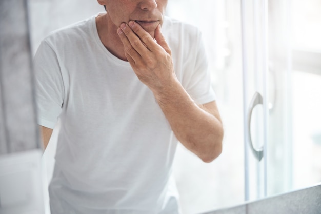 鏡の前で手をあごに触る男性