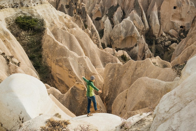 Turista maschio che equilibra le valli rosse e rosa della cappadocia. montagne di arenaria magiche e paesaggi di grotte vicino a goreme.