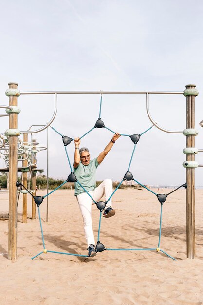 Male tourist climbing in exercise area on beach