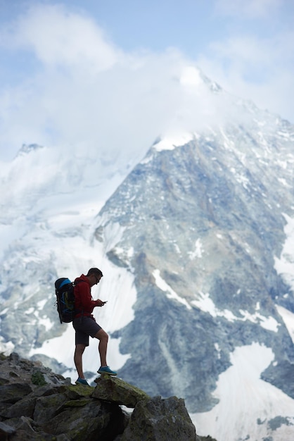 Male tourist climbing snowy rocky cliffs of beautiful Penning Alps in Switzerland