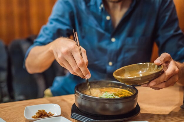 Turista maschio che mangia noodles coreani in un caffè coreano travel korea concept